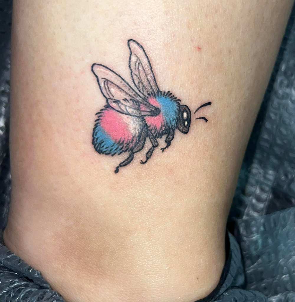 This is a picture of the bumblebee tattoo I got that has the colors of the transgender flag on its body instead of the traditional bumblebee colors.
